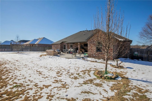 snow covered back of property featuring a patio area and an outdoor living space