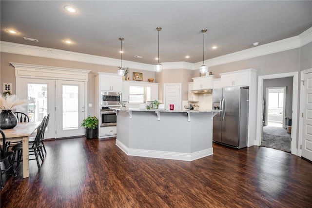 kitchen featuring a kitchen island, appliances with stainless steel finishes, pendant lighting, and white cabinetry