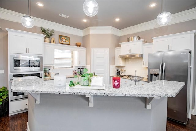 kitchen with white cabinets, stainless steel appliances, a large island with sink, and hanging light fixtures