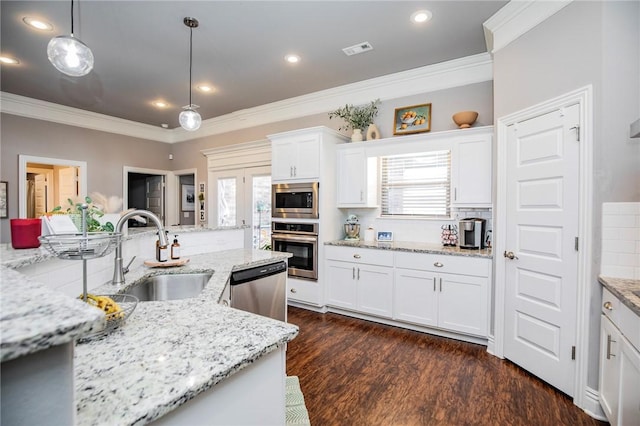 kitchen with decorative light fixtures, backsplash, white cabinets, appliances with stainless steel finishes, and sink