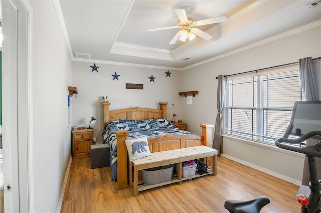 bedroom with ceiling fan, light hardwood / wood-style flooring, ornamental molding, and a tray ceiling