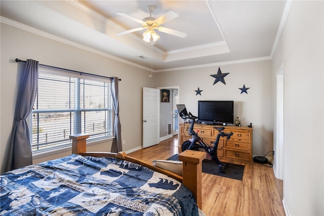 bedroom with ceiling fan, ornamental molding, a raised ceiling, and wood-type flooring