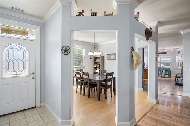 entryway with light wood-type flooring, a notable chandelier, and crown molding