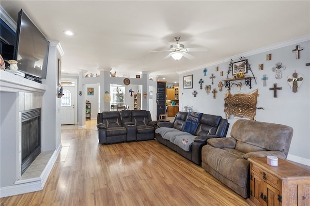 living room featuring a tile fireplace, ceiling fan, light hardwood / wood-style floors, and crown molding