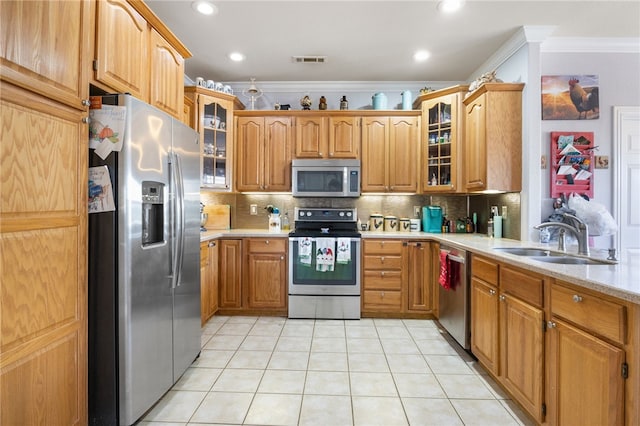 kitchen with backsplash, ornamental molding, appliances with stainless steel finishes, light tile patterned flooring, and sink