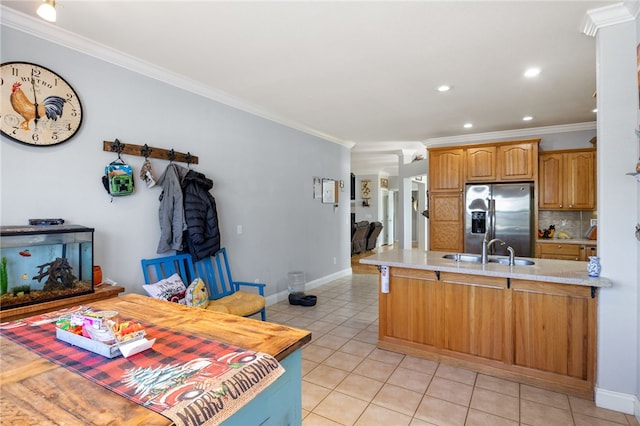 kitchen with sink, a kitchen breakfast bar, ornamental molding, light tile patterned floors, and stainless steel refrigerator with ice dispenser