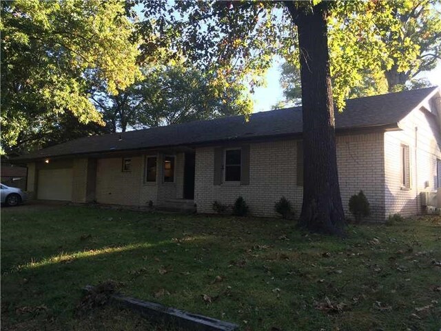 single story home featuring a front lawn and a garage