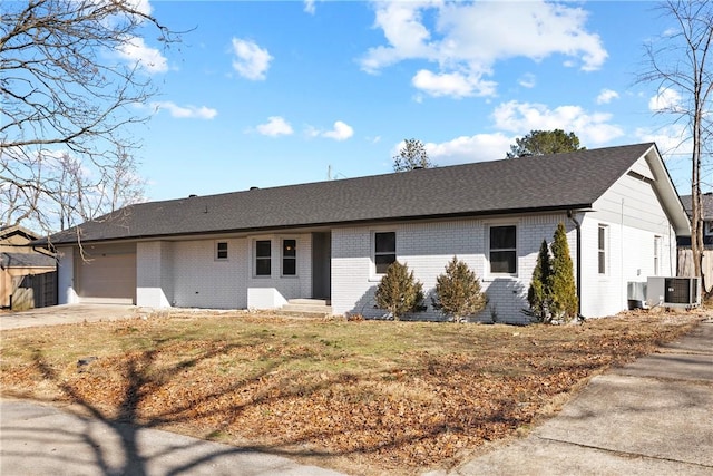 ranch-style home featuring a garage, a front yard, and central air condition unit