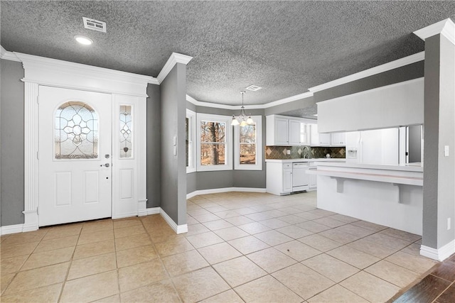 entryway with crown molding, an inviting chandelier, and light tile patterned floors