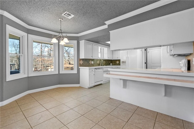 kitchen featuring white cabinetry, a kitchen breakfast bar, hanging light fixtures, light tile patterned floors, and white appliances