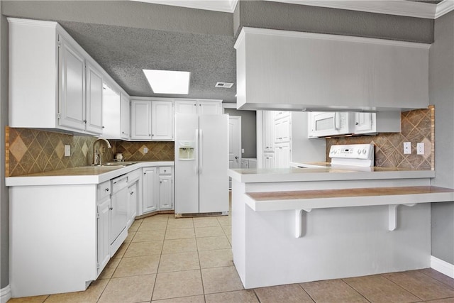 kitchen with white cabinetry, white appliances, a breakfast bar, and kitchen peninsula