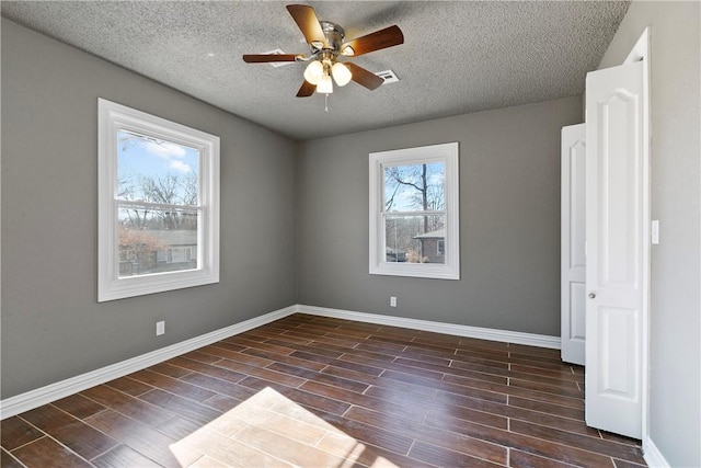 empty room with ceiling fan, a textured ceiling, and a wealth of natural light