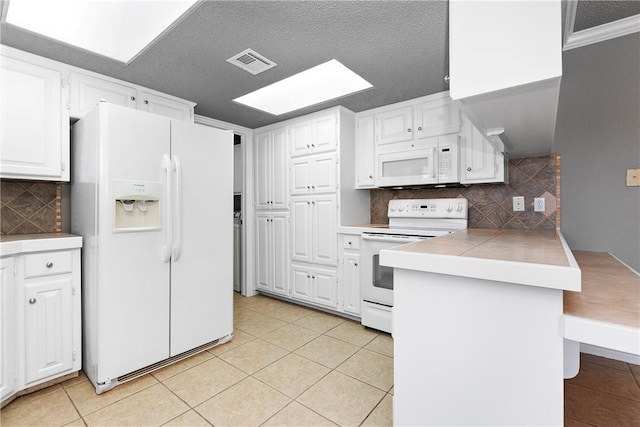 kitchen with tasteful backsplash, white cabinetry, light tile patterned floors, and white appliances