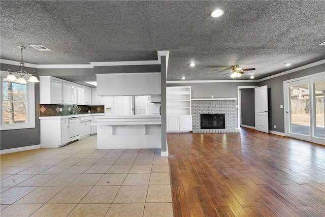 kitchen with hanging light fixtures, white dishwasher, a kitchen island, decorative backsplash, and white cabinets