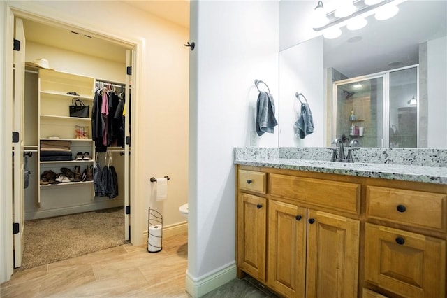 bathroom featuring toilet, walk in shower, and vanity