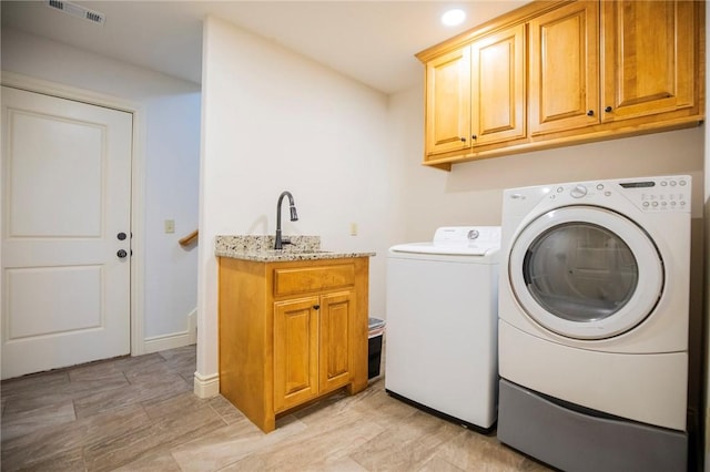 washroom with washer and dryer, cabinets, and sink