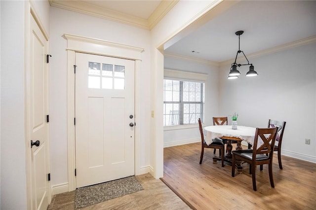 entrance foyer with ornamental molding, light hardwood / wood-style flooring, and an inviting chandelier