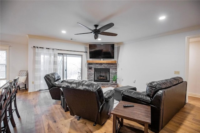 living room with a fireplace, light wood-type flooring, ceiling fan, and a healthy amount of sunlight