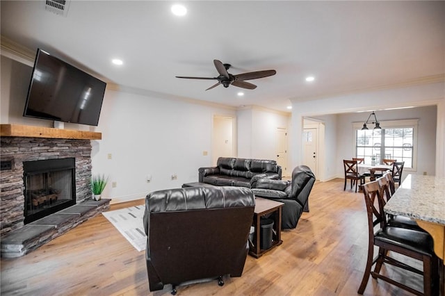 living room featuring a fireplace, ceiling fan, light wood-type flooring, and crown molding