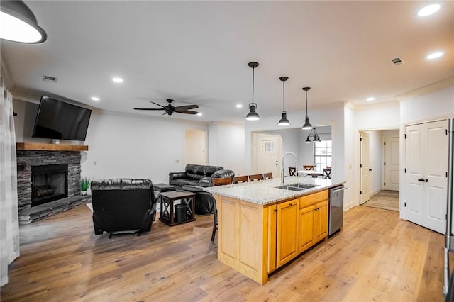 kitchen featuring dishwasher, sink, an island with sink, ceiling fan, and a stone fireplace