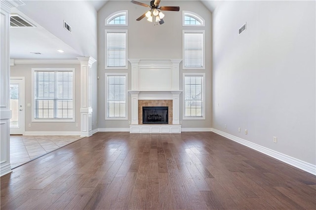 unfurnished living room featuring a towering ceiling, a fireplace, ceiling fan, and hardwood / wood-style flooring