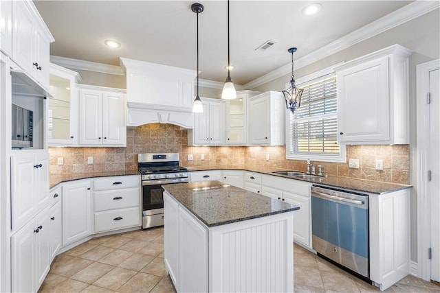 kitchen with white cabinets, a center island, dark stone counters, and appliances with stainless steel finishes