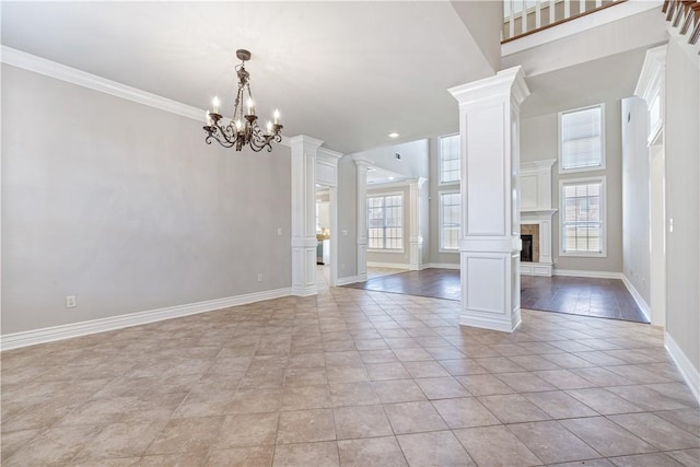 interior space featuring a tiled fireplace, crown molding, a chandelier, and ornate columns