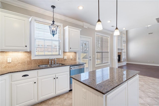 kitchen with dishwasher, decorative light fixtures, white cabinets, dark stone counters, and sink