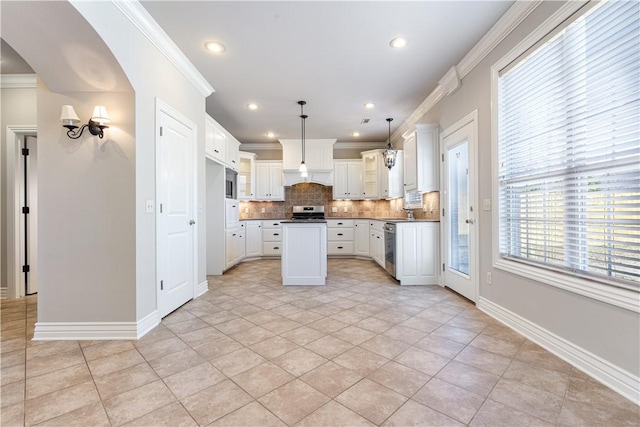 kitchen with stainless steel appliances, decorative light fixtures, white cabinets, decorative backsplash, and a kitchen island