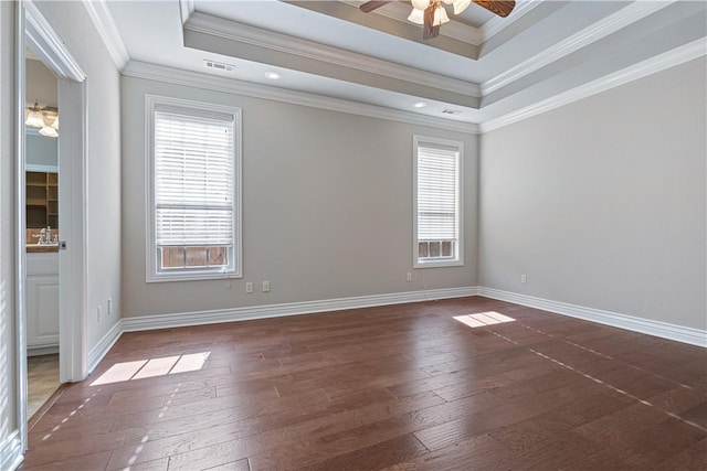 empty room with ornamental molding, dark wood-type flooring, a raised ceiling, and ceiling fan