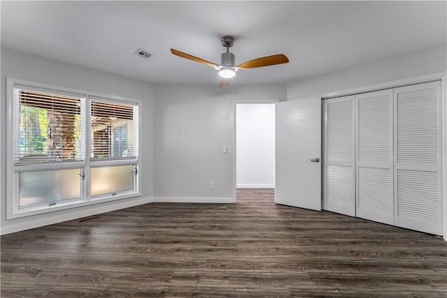 unfurnished bedroom featuring ceiling fan, a closet, and dark wood-type flooring