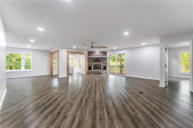 unfurnished living room with ceiling fan, dark wood-type flooring, plenty of natural light, and a fireplace