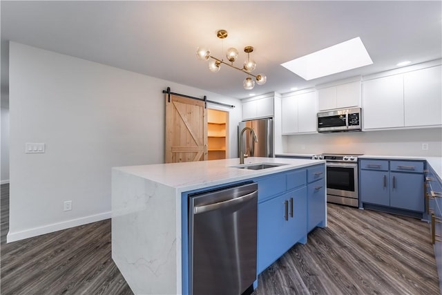 kitchen featuring stainless steel appliances, a barn door, white cabinetry, and a kitchen island with sink