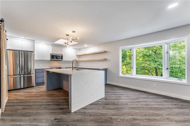 kitchen featuring pendant lighting, sink, white cabinetry, a kitchen island with sink, and appliances with stainless steel finishes