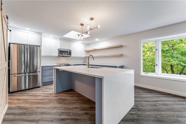 kitchen with a barn door, pendant lighting, sink, appliances with stainless steel finishes, and white cabinets