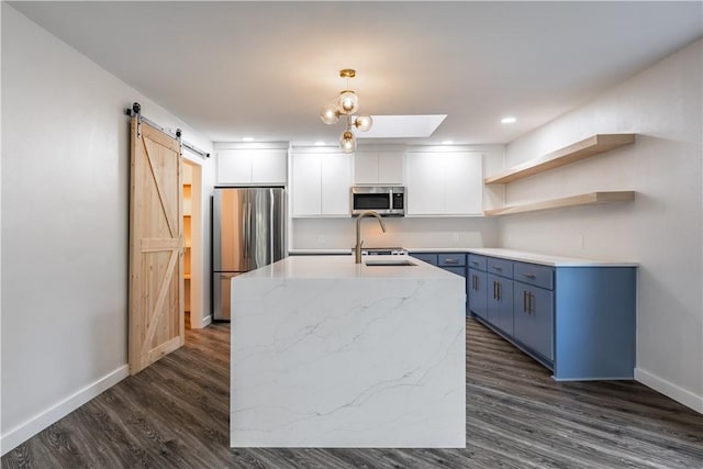 kitchen featuring appliances with stainless steel finishes, decorative light fixtures, white cabinetry, blue cabinetry, and a barn door