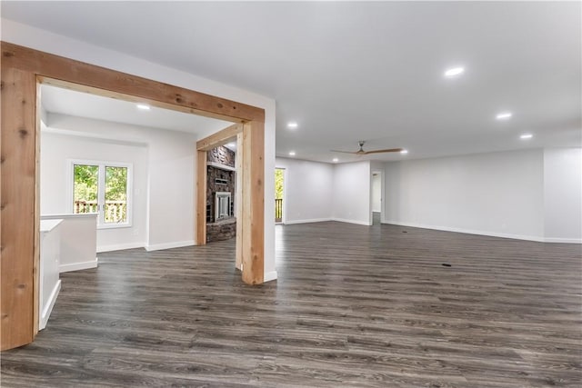 unfurnished living room with ceiling fan, a large fireplace, and dark hardwood / wood-style floors