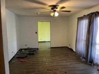 empty room with ceiling fan and dark wood-type flooring