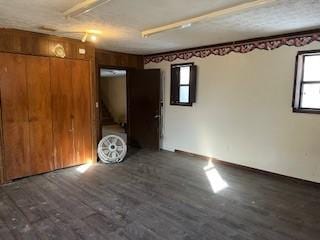 unfurnished room with a textured ceiling, dark hardwood / wood-style flooring, and wooden walls