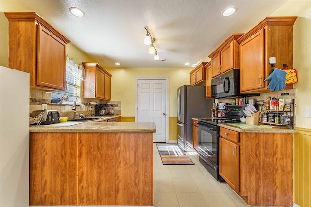 kitchen with backsplash, kitchen peninsula, black appliances, and sink