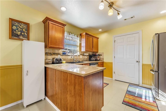 kitchen with stainless steel appliances, sink, light stone counters, tasteful backsplash, and kitchen peninsula