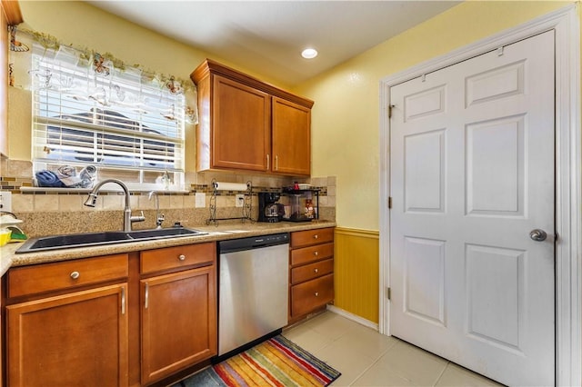 kitchen featuring backsplash, stainless steel dishwasher, light tile patterned floors, and sink