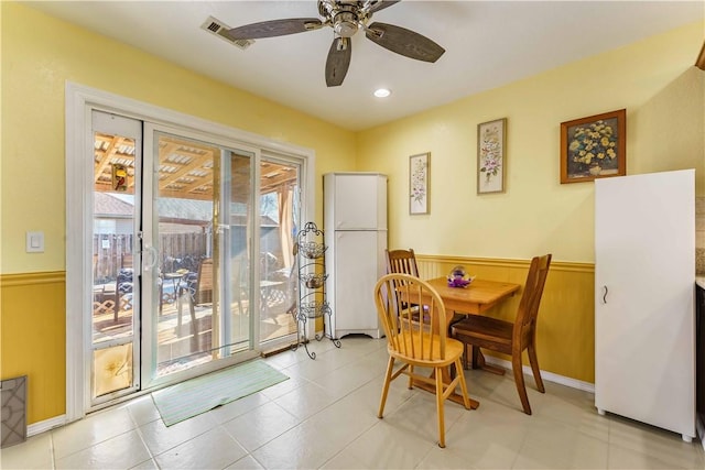 dining space with wood walls and ceiling fan