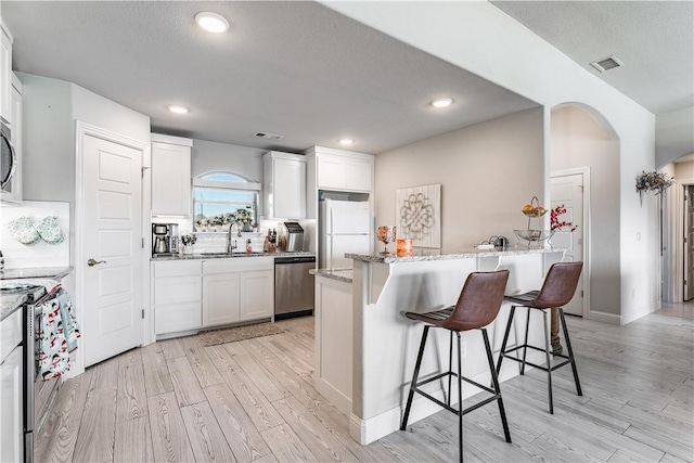 kitchen featuring light hardwood / wood-style flooring, a center island, white cabinetry, appliances with stainless steel finishes, and sink