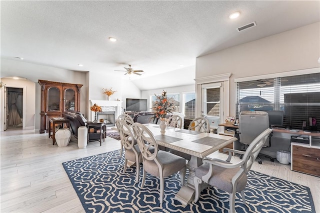 dining room featuring lofted ceiling, a textured ceiling, ceiling fan, and light hardwood / wood-style flooring