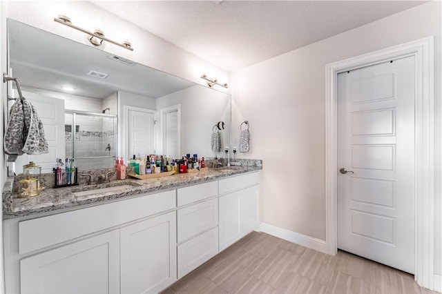 bathroom featuring an enclosed shower, vanity, and a textured ceiling