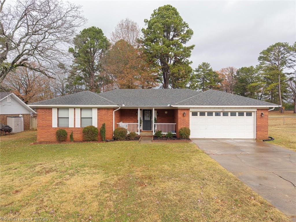 ranch-style house featuring covered porch, a garage, and a front yard