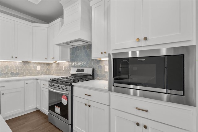 kitchen featuring custom exhaust hood, white cabinetry, and stainless steel gas range