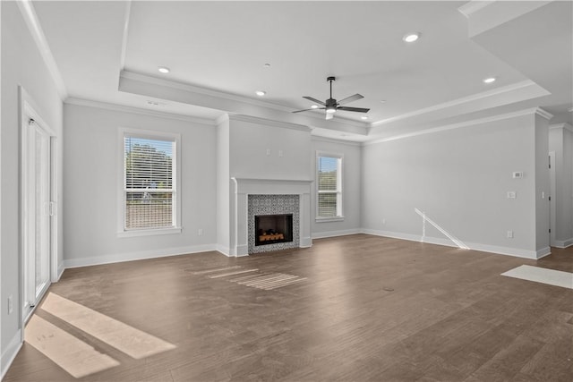 unfurnished living room featuring a raised ceiling, a tile fireplace, ornamental molding, and dark hardwood / wood-style floors