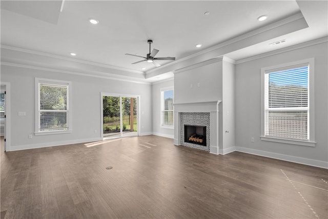 unfurnished living room with a tile fireplace, ornamental molding, a healthy amount of sunlight, and ceiling fan